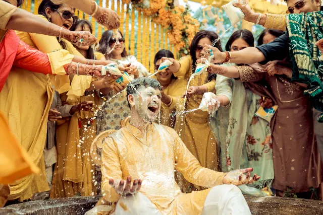 Haldi, the groom laughing as the colour is thrown