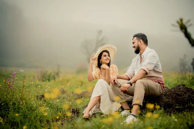 The couple seated in a field of yellow flowers